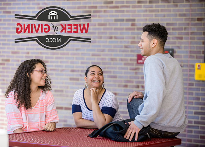 Three students sitting in front of brick wall chatting